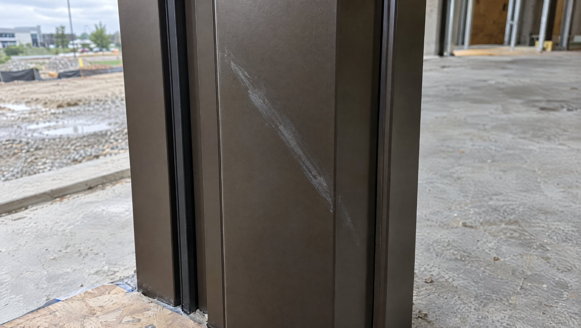 Rub mark on a dark bronze painted aluminum storefront jamb on a jobsite, before anodized aluminum scratch repair is considered