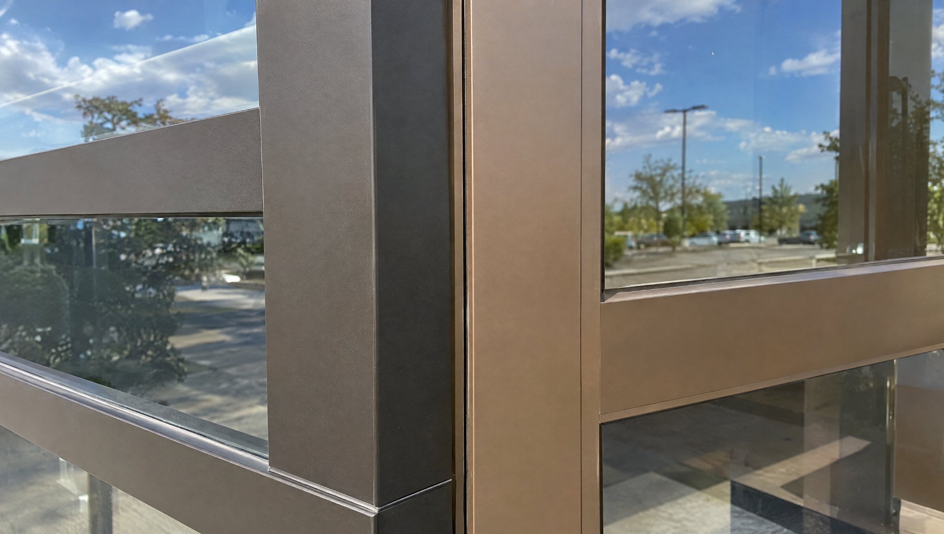 Dark bronze anodized storefront frame next to a bronze painted door stile with a visible color mismatch, the finish is close enough assumption a PM makes before fabrication
